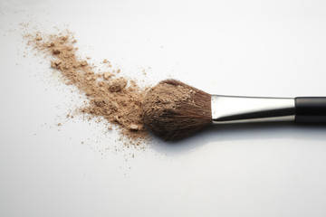 Makeup Brush with beige loose Face Powder on white background