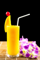 Mango juice and fruit on glass near flower isolation black backg
