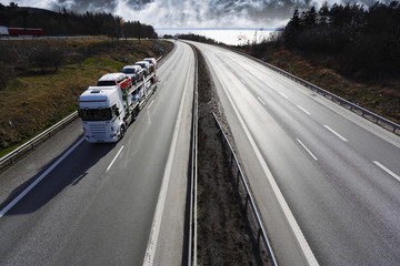 Fototapeta na wymiar truck transporting new cars on a scenic highway, early evening