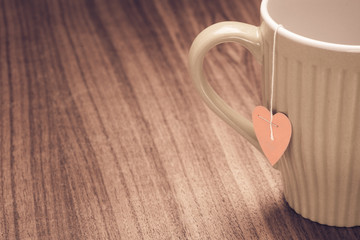 Tea mug on rustic wooden table with heart shaped label