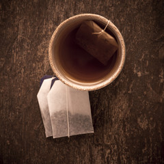 Teacup filled with hot tea and teabag on rustic wooden table