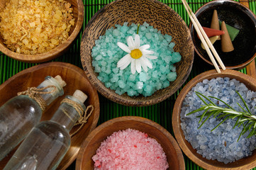 colorful sea salt ,oil , in wooden bowl with Gerbera on mat
