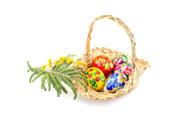 Easter eggs and basket with a sprig of mimosa