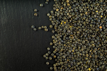 Green lentils on the black deck. Copy space