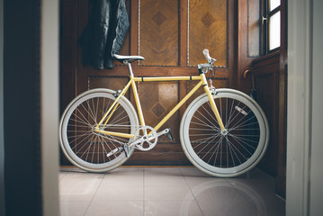 Fototapeta na wymiar A yellow fixed-gear bicycle (also called fixie) at home