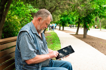Fototapeta premium old man with tablet sitting on a bench