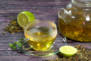 Tea in a glass teapot and a transparent cup with lime and mint