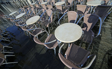 many chairs of the outdoor cafes with water at high tide