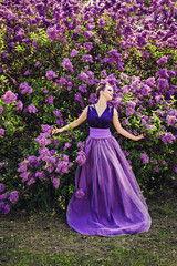 Obraz na płótnie Canvas Beautiful girl in lilac ball dress among the flowers