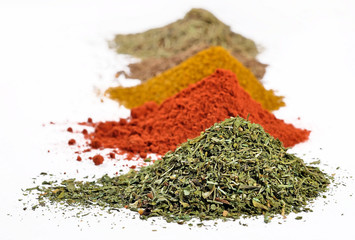 Heaps of different dry spices on a white
