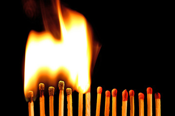 Line of lighted matches on black background