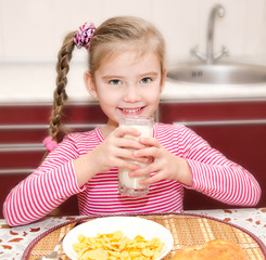 Cute little girl having breakfast drinking milk