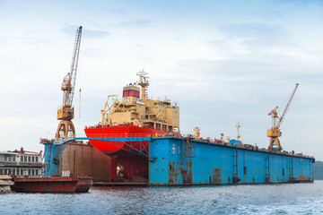 Fototapeta premium Floating blue dry dock with red tanker under repair