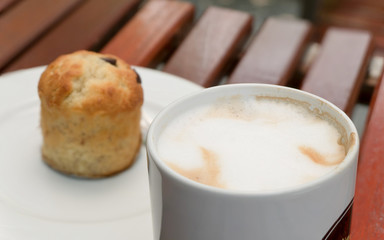 Coffee cup on wooden tables with muffin background