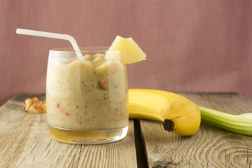 Banana and celery smoothie with berries on wooden table
