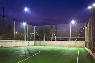 Basketball court illuminated at dusk