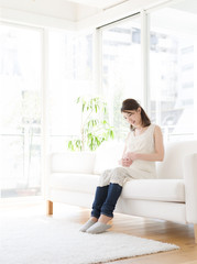 ソファに座る若い妊婦