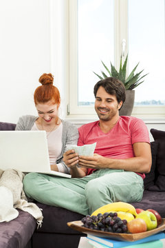 Couple at the Couch with Laptop, Card and Money