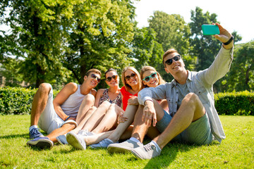 smiling friends with smartphone making selfie