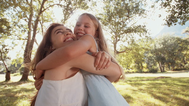 Happy girl and her mom sharing a loving hug outdoors