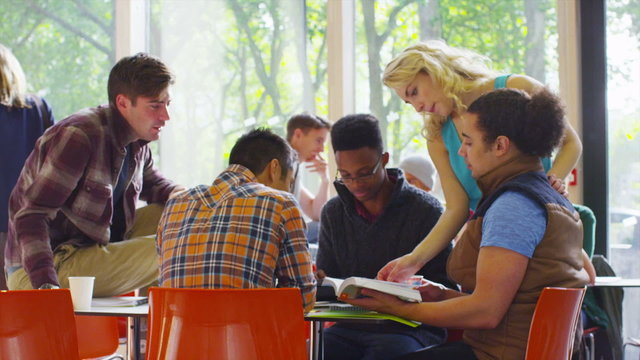 Cheerful diverse student group chatting & working together in college cafe area