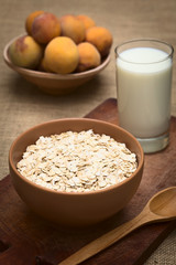 Bowl full of rolled oats with a glass of milk and peaches