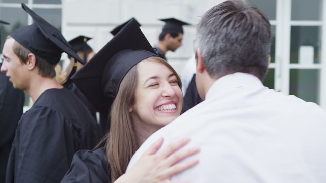 Happy students on graduation day are hugged and congratulated by proud parents