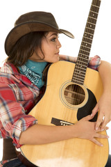 woman cowgirl with guitar arms around look to side