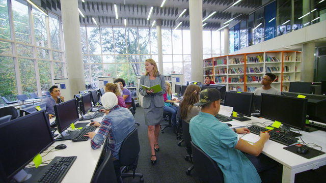 Student group listening to the teacher and working in a room full of computers