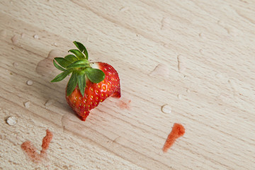 Eaten isolated strawberry head on a wooden background