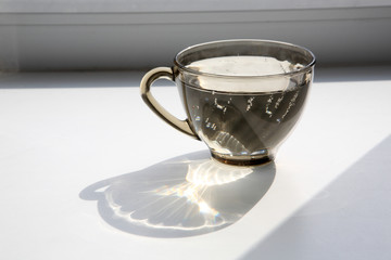 A glass of water on the windowsill in the sunlight.