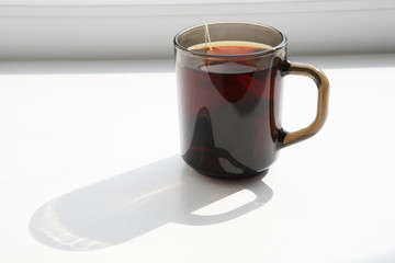 A cup of tea on the windowsill in the sunlight.