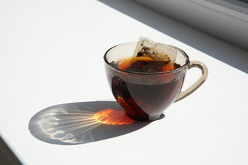 A cup of tea on the windowsill in the sunlight.