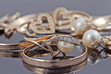 Naklejka premium gold ring with pearl lies in background of other gold jewelry