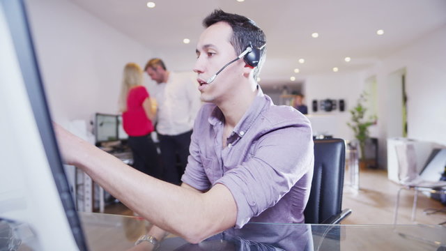 Young creative professional worker liaises with clients via a head set