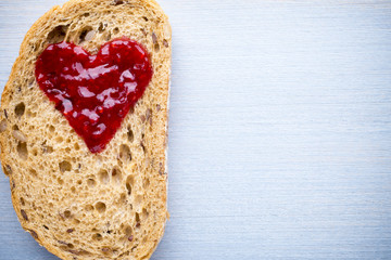 Grain slice of bread with jam heart shape.