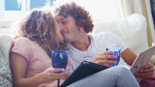 Couple relaxing at home with computer tablet and a glass of wine