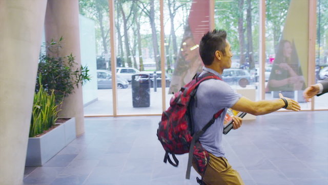 Cheerful student arrives for an interview at large modern college or university.