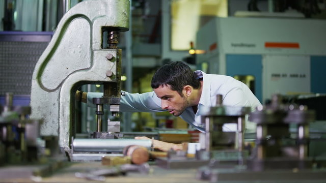Young male machine operator working in a factory