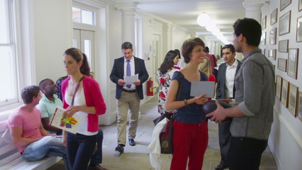 Mixed ethnicity group of students chatting in the hallway between classes