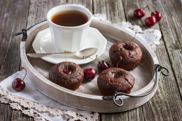 cherry cupcakes and cup of tea on a wooden tray
