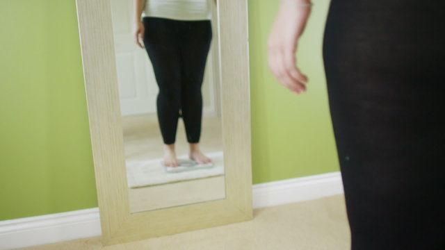 Plus size woman with positive body image stepping on scale
