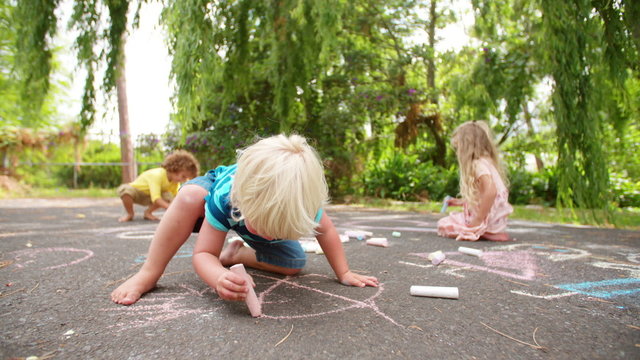 Boy drawing chalk pictures on a walkway in a park