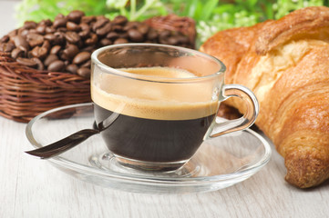 coffee in glass cup with croissants and coffee beans