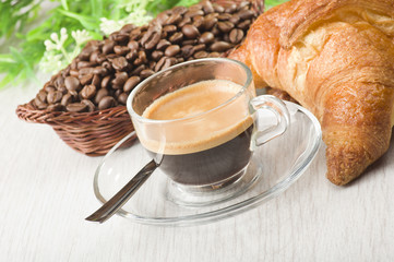 coffee in glass cup with croissants and coffee beans