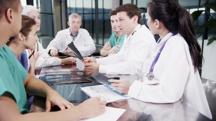 Multi ethnic medical team in a meeting discuss a patient's x-ray results - Powered by Adobe