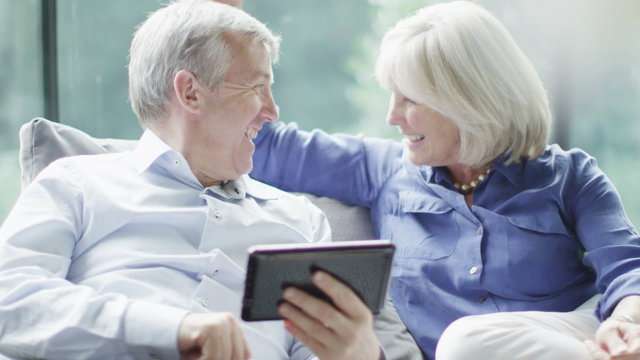 Attractive mature couple with technology shopping on the internet at home
