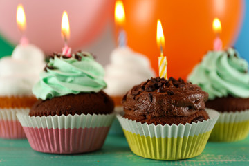 Delicious birthday cupcakes on table on bright background