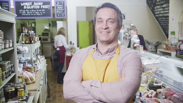 Portrait of a happy male shopkeeper in a delicatessen or food store