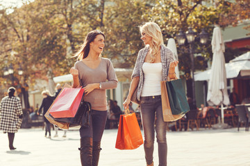 Two beautiful women walking down the street after shopping